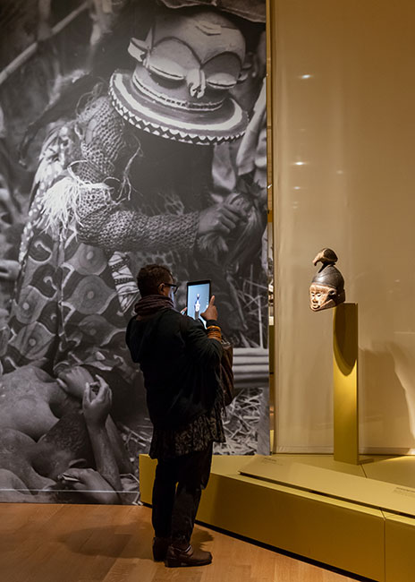 visitor taking a photo of a Congo mask at the exhibition